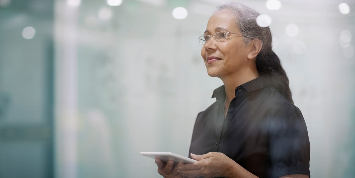 professional woman in office smiling, holding a tablet