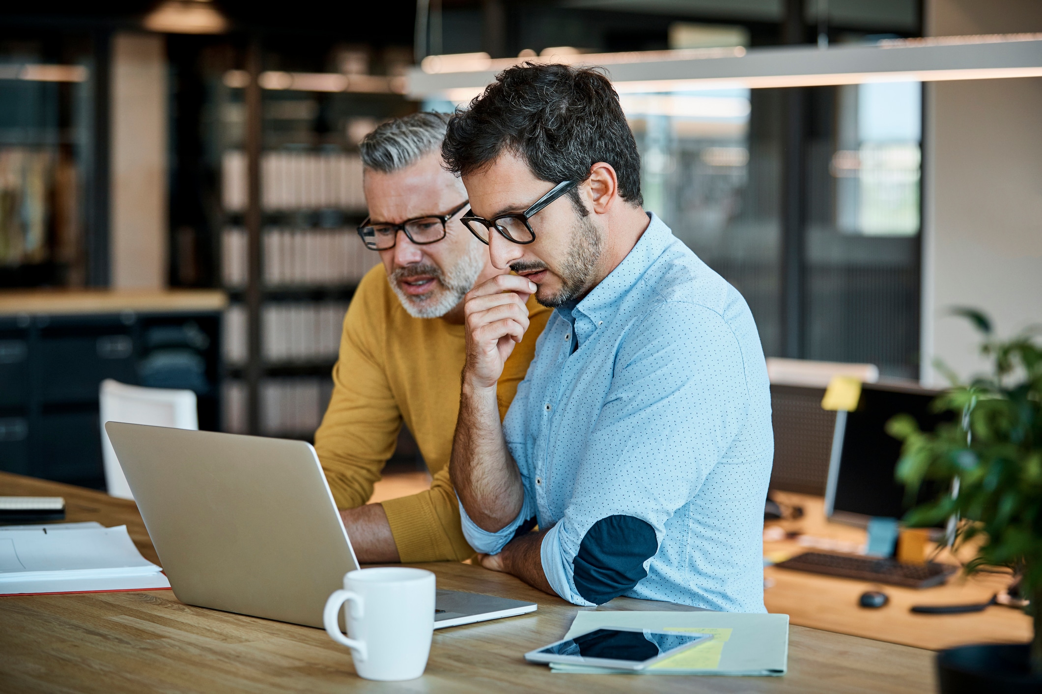 two people with glasses staring at a computer