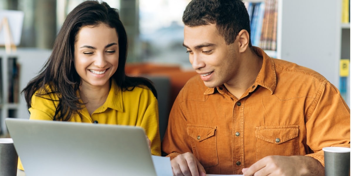 two people working on a laptop, smiling